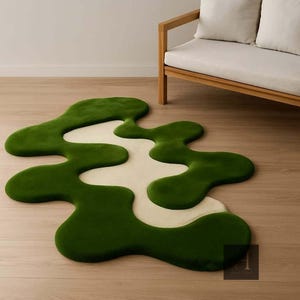 May include: A unique, abstract rug with a flowing, organic design. The rug features a vibrant green border that surrounds a cream-colored center. The rug is placed on a light-colored wooden floor, with a wooden sofa in the background.