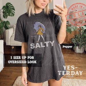Vintage 90s style "Salty Girl" typography graphic, coastal beach aesthetic with a distressed retro look, printed on a Comfort Colors garment-dyed tee, feminine summer streetwear.