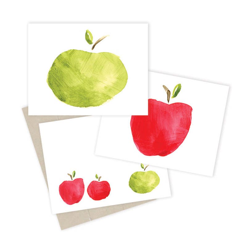 May include: Set of three blank note cards featuring watercolor illustrations of apples. One card has a green apple, one card has a red apple, and one card has two small red apples.