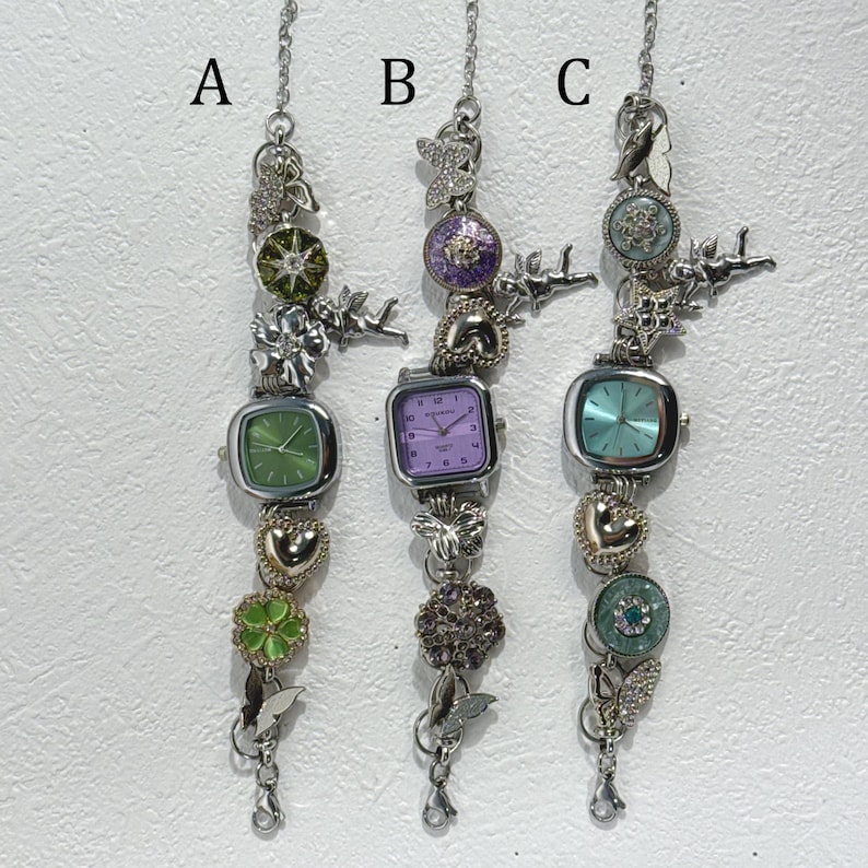 May include: Three silver-toned charm bracelets with square-faced watches. Each bracelet features decorative charms, including hearts, butterflies, and floral accents. The watch faces are green, purple, and teal.