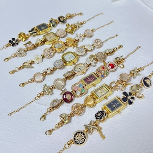 May include: A collection of gold-toned bracelet watches with various decorative elements. Each watch features a different face shape and is adorned with floral, gem, and butterfly accents. The bracelets have a delicate chain design.