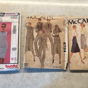 Könnte beinhalten: Drei Vintage-Schnittmusterumschläge, die nebeneinander angeordnet sind. Der linke Umschlag ist ein Burda 8995 Kleiderschnittmuster. Der mittlere Umschlag ist ein McCall's 6724 Anzugschnittmuster. Der rechte Umschlag ist ein McCall's 6682 Schnittmuster.