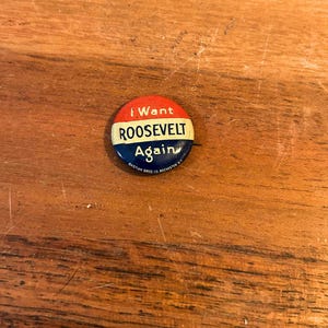 Könnte beinhalten: Ein runder politischer Ansteckbutton mit horizontalen Streifen in Rot, Weiß und Blau. Der Text lautet I Want in Rot, ROOSEVELT in Schwarz auf dem weißen Streifen und Again in Weiß auf dem blauen Streifen, mit BASTIAN BROS CO. ROCHESTER N.Y. unten.