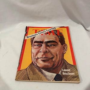 May include: A vintage TIME magazine cover featuring a portrait of Leonid Brezhnev against a yellow background. The cover has the headline "Brezhnev Comes Courting" and the TIME logo. The magazine is in good condition.