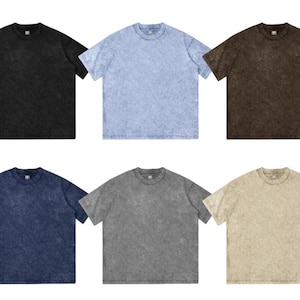 May include: Six short-sleeved t-shirts in various colors: black, light blue, brown, navy blue, gray, and tan. Each shirt has a crew neck and a textured, faded appearance, suggesting a vintage or washed style.