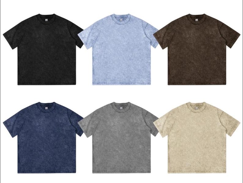 May include: Six short-sleeved t-shirts in various colors: black, light blue, brown, navy blue, gray, and tan. Each shirt has a crew neck and a textured, faded appearance, suggesting a vintage or washed style.