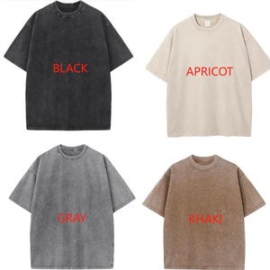 May include: Four short-sleeved t-shirts in black, apricot, gray, and khaki. Each shirt has a crew neck and the color name printed in red. The shirts have a slightly faded, vintage look.