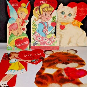 May include: Vintage Valentine's Day cards featuring illustrations of a fairy, a girl with a beet, a white cat, a girl with a heart, and a tiger holding a heart. The cards are red, white, yellow, and blue.