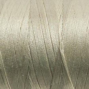 May include: Close-up of a spool of light green thread. The thread is tightly wound, with visible parallel strands creating a textured surface. The color is a muted, neutral green, suitable for various sewing projects.