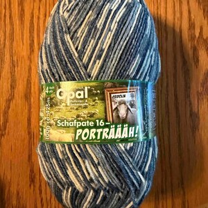 May include: A skein of variegated blue, white, and grey yarn with a paper label featuring the text Opal, 4-ply, 100g ca. 425m, Schafpate 16, and PORTRÄÄÄH!. The label displays a picture of a sheep in a frame and a flock of sheep in a field.