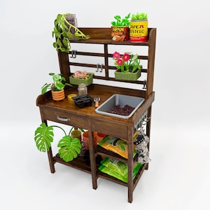May include: A miniature wooden potting bench with a dark stain. It features shelves, a sink, and hooks for tools. The bench is decorated with small plants, including a monstera leaf, and miniature cans of food. A charming addition to any dollhouse or miniature garden.