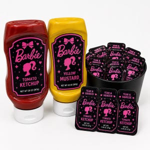 Puede incluir: Una colección de condimentos con temática Barbie, que incluye una botella de ketchup de tomate roja, una botella de mostaza amarilla y paquetes individuales de ketchup. Las botellas y los paquetes presentan el logotipo y la silueta de Barbie en rosa.