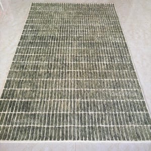 May include: A rectangular rug featuring a geometric design of vertical lines in green and white hues. The rug has a textured finish, and the words "KashiRugs" are visible in several places.