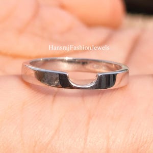 May include: A silver-colored ring with a curved design. The ring has a smooth, polished surface and a unique shape. The text "HansrajFashionJewels" is visible on the image. This ring is a piece of jewelry.