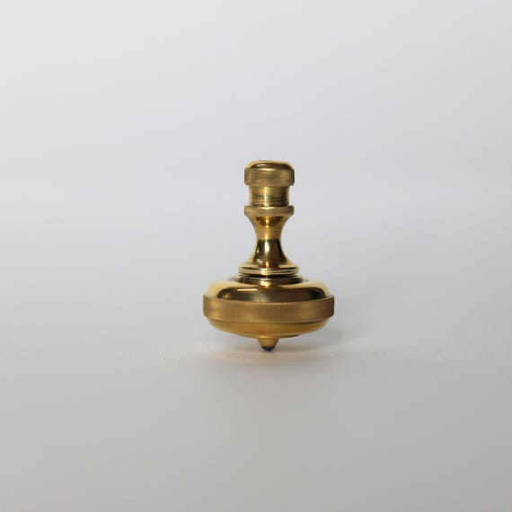 A hand-machined precision brass spinning top engineered to spin for 3 full minutes — the kind of object you pick up and never put down.