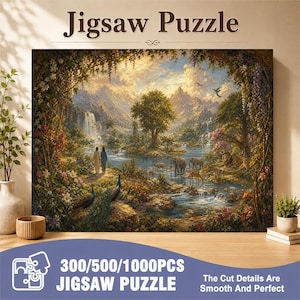 Op de afbeelding: Een legpuzzel met een landschapsschilderij van een weelderige tuin met een rivier, bergen, watervallen en diverse dieren zoals olifanten, een leeuw en pauwen. Twee figuren staan op een pad. De tekst luidt Jigsaw Puzzle en 300/500/1000PCS.
