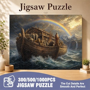Op de afbeelding: Een rechthoekige legpuzzel met een gedetailleerde illustratie van een grote houten ark vol dieren op een stormachtige zee, met een regenboog aan de lucht. De tekst Jigsaw Puzzle staat bovenaan en 300/500/1000PCS JIGSAW PUZZLE onderaan.
