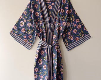 May include: A blue floral print robe with pink flowers and green leaves. The robe has a striped trim and a matching belt. The robe is hanging on a wooden hanger.