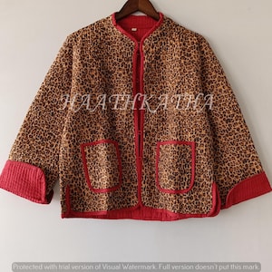 May include: A leopard print jacket in brown and tan, featuring red trim and pockets. The jacket has a mandarin collar and is fastened with buttons. The sleeves are cuffed with red fabric. The text "HAATHKATHA" is printed on the jacket.