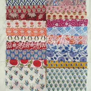Pode incluir: Uma coleção de peças de tecido dobradas com vários padrões coloridos. Os designs incluem motivos florais, geométricos e de pinguins em tons de vermelho, azul, laranja e rosa. Os tecidos estão dispostos de forma organizada, mostrando as diversas estampas.