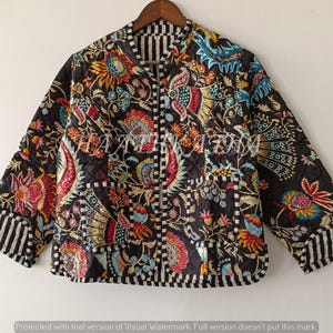 May include: A black quilted jacket with a colourful floral design in red, yellow, blue, and green. The jacket has a zip-up front, a stand-up collar, and striped cuffs. The jacket is approximately 71 cm long.