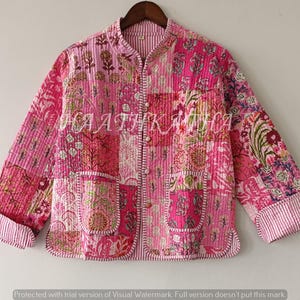 Peut inclure: Veste rose en patchwork avec des motifs floraux et géométriques. La veste a des manches longues, deux poches et une fermeture boutonnée. Les poignets et le col sont rayés. Le texte "HAATIK" est visible.