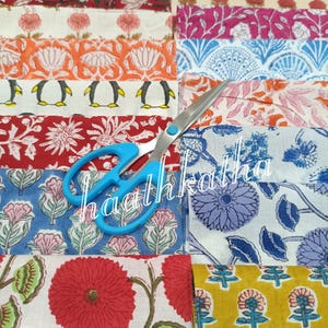May include: Assortment of colorful fabric swatches with various floral and penguin patterns. A pair of blue-handled scissors rests on top of the fabric. The word "haathkatha" is visible on the fabric.