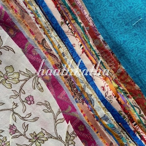 May include: A selection of patterned fabric strips in various colours, including pink, blue, orange, and gold. The strips are arranged diagonally, with floral and other designs. The text "haathkatha" is visible in the image.