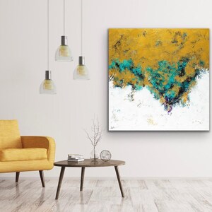 May include: Abstract art piece with a textured surface. The artwork features a blend of gold, teal, black, and white colors. The painting is displayed on a white wall above a yellow armchair and a small wooden table.