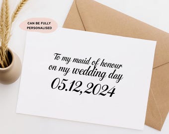 May include: A white rectangular greeting card with black text that reads To my maid of honour on my wedding day 05.12.2024. The card is accompanied by a tan envelope and a small pink oval label with the text CAN BE FULLY PERSONALISED.