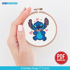 May include: A cross-stitch embroidery hoop featuring a blue cartoon character with large ears and pink hearts. The hoop is 3 inches (7.5 cm) in diameter. The image includes the text "PDF DOWNLOAD" and the website address "www.labpattern.com".