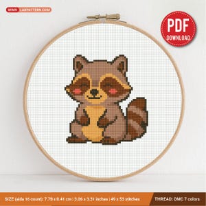 Puede incluir: Un patrón de punto de cruz de un mapache de dibujos animados en un bastidor de bordado de madera. El mapache es marrón, beige y negro con mejillas rosadas. El patrón mide 7,78 x 8,41 cm (3,06 x 3,31 pulgadas) y utiliza 7 colores DMC. Incluye el texto "PDF DOWNLOAD".