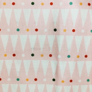May include: Pink fabric with a repeating pattern of white triangles and colorful dots. The dots are in red, green, yellow, and black, creating a playful and geometric design.