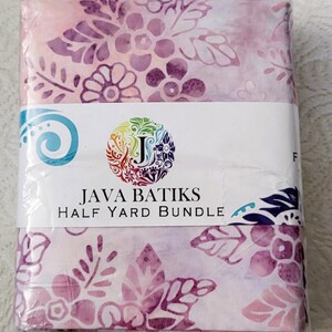 May include: A half-yard bundle of Java Batiks fabric, wrapped in clear plastic. The fabric features a floral pattern in shades of pink and purple. The label includes the brand name and a colorful logo.