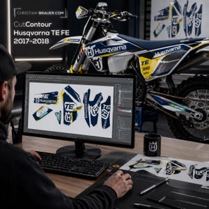 May include: A computer monitor displaying a digital design file for Husqvarna TE FE 2017-2018 motorcycle decals. The screen shows various blue, white, and yellow graphic shapes. A physical Husqvarna motorcycle is visible in the background.