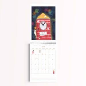 Peut inclure: Un calendrier mural pour janvier illustrant une fus&eacute;e rouge avec un chien blanc portant des lunettes de soleil dans le cockpit. La fus&eacute;e porte le texte MOND RAKETE et est entour&eacute;e de feux d'artifice color&eacute;s sur un ciel nocturne bleu &eacute;toil&eacute;.