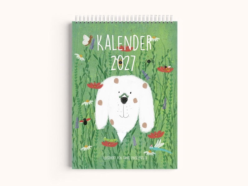 Peut inclure: Un calendrier mural &agrave; spirale intitul&eacute; KALENDER 2027 illustr&eacute; d'un chien blanc &agrave; taches brunes entour&eacute; d'herbe verte, de coquelicots rouges, de marguerites blanches et de divers petits insectes dont un papillon, une abeille et une libellule.