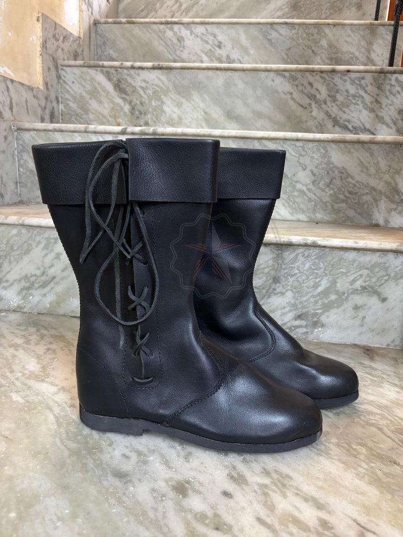 Artisan leather tall boots styled on wooden surface historical vibe.