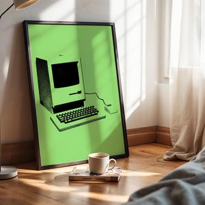 May include: A framed wall art print featuring a black graphic illustration of a vintage personal computer with a monitor, keyboard, and mouse centred on a solid light green background. The artwork is enclosed in a thin black frame.