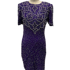 May include: A purple sequined dress with short sleeves and a round neckline. The bodice features a floral pattern with silver beading. The dress is displayed on a mannequin.