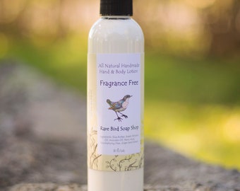 Peut inclure: Une bouteille en plastique blanche de lotion pour les mains et le corps sans parfum avec un bouchon pompe noir. L'étiquette est de couleur crème avec une illustration d'oiseau et le texte "All Natural Handmade Hand & Body Lotion Fragrance Free Rare Bird Soap Shop 8 fl/oz".