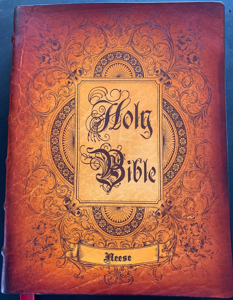 May include: A brown leather-bound Holy Bible with ornate gold detailing and the name "Neese" embossed on a ribbon banner.