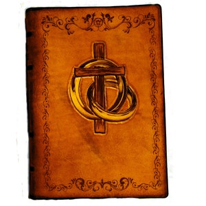 May include: A brown leather journal with a decorative border and a cross with two rings around it.