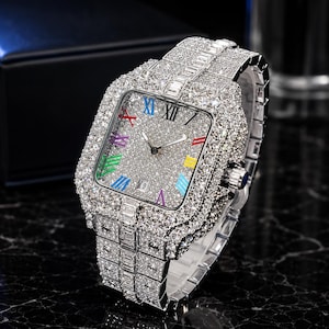Peut inclure: Une montre-bracelet argentée avec un cadran carré et un bracelet entièrement incrustés de pierres transparentes scintillantes. Le cadran présente une surface texturée et pailletée avec des chiffres romains multicolores et un guichet de date.