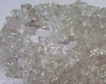 May include: A strand of clear quartz crystal chips. The chips are irregular in shape and size, and they have a translucent appearance. The chips are strung together to form a necklace or bracelet.
