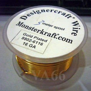 K&ouml;nnte beinhalten: Eine Spule mit vergoldetem Draht, beschriftet mit "Designercraft Wire", "Monsterkraft.com", "Gold Plated 8802-6116 16 GA" und "1 Meter Spule".