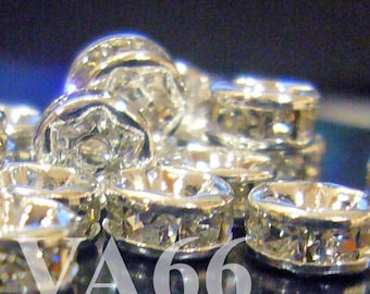 May include: Close-up of a group of silver-toned metal bead caps with clear crystal rhinestones. The bead caps are arranged in a pile, with some overlapping.
