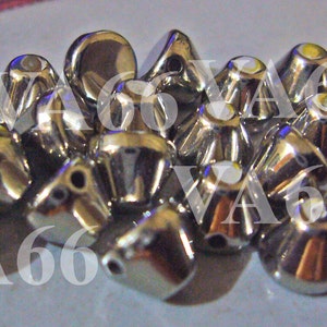 May include: A group of silver metal beads with a pointed top and a flat bottom. The beads have a shiny finish and are arranged in a pile.