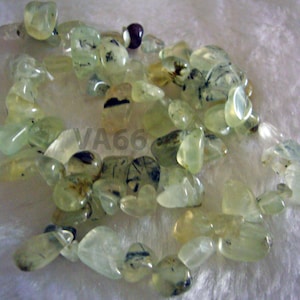 May include: A strand of light green and black gemstone beads. The beads are irregularly shaped and have a translucent appearance.