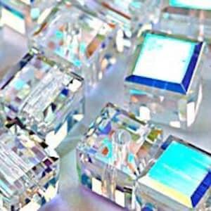 Könnte beinhalten: Eine Gruppe von quadratischen, durchsichtigen, irisierenden Glasfliesen mit abgeschrägten Kanten. Die Fliesen sind in einem zufälligen Muster angeordnet.